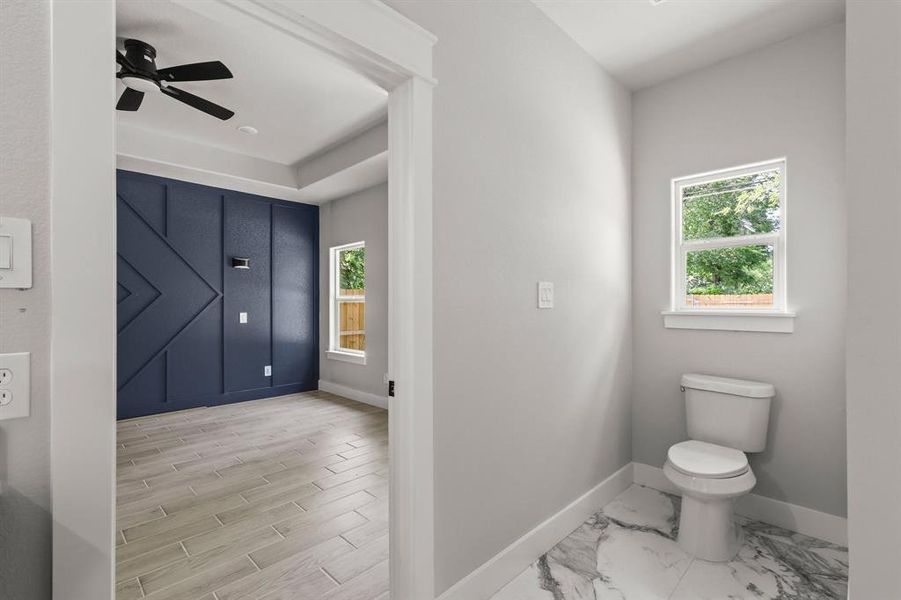 Bathroom with baseboards, healthy amount of natural light, toilet, and a ceiling fan