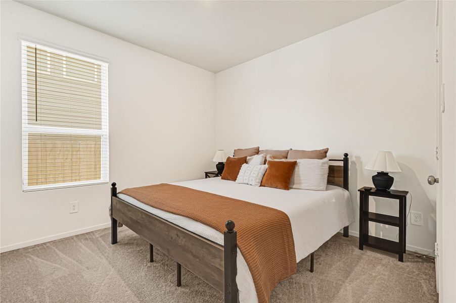 Cozy bedroom featuring a stylish bed with neutral bedding, soft carpeting, and ample natural light from a large window. Cozy bedroom featuring a stylish bed with neutral bedding, soft carpeting, and ample natural light from a large window.