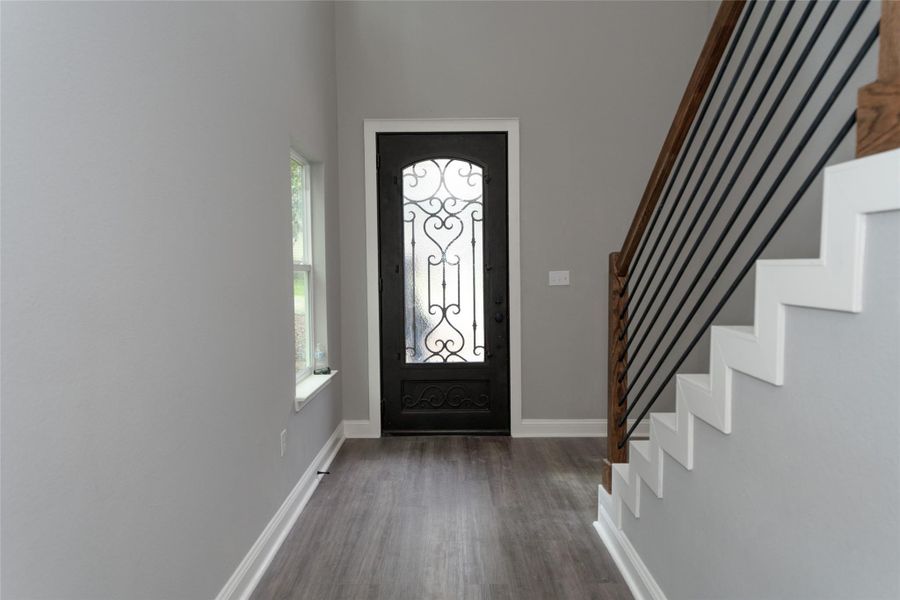 This inviting entryway is bathed in natural light, with wood-look flooring and recessed lighting creating a warm, welcoming feel. A beautiful door with a glass window opens to let in fresh air, offering a seamless connection to the outdoors.