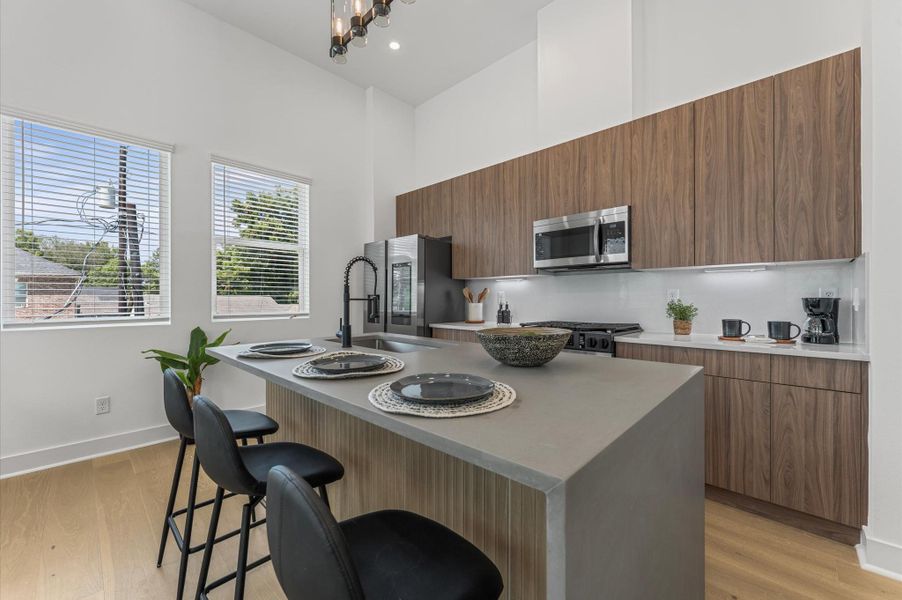 The heart of the second-floor open-concept living, dining, and kitchen, this spacious kitchen island features sleek modern finishes, including a one-sided cascade quartz countertop, a farmhouse sink, and stylish pendant lighting, with a built-in seating area perfect for casual breakfasts or chatting with family and friends.