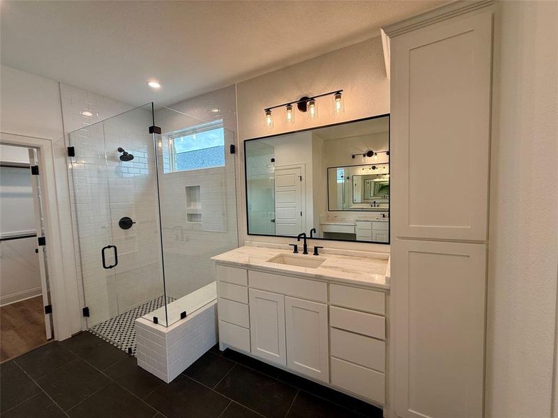Bathroom with vanity, a stall shower, dark tile patterned flooring, and a walk in closet