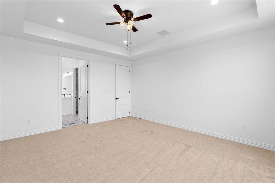 Unfurnished bedroom featuring a raised ceiling, light colored carpet, recessed lighting, ensuite bath, and ceiling fan Unfurnished bedroom featuring a raised ceiling, light colored carpet, recessed lighting, ensuite bath, and ceiling fan