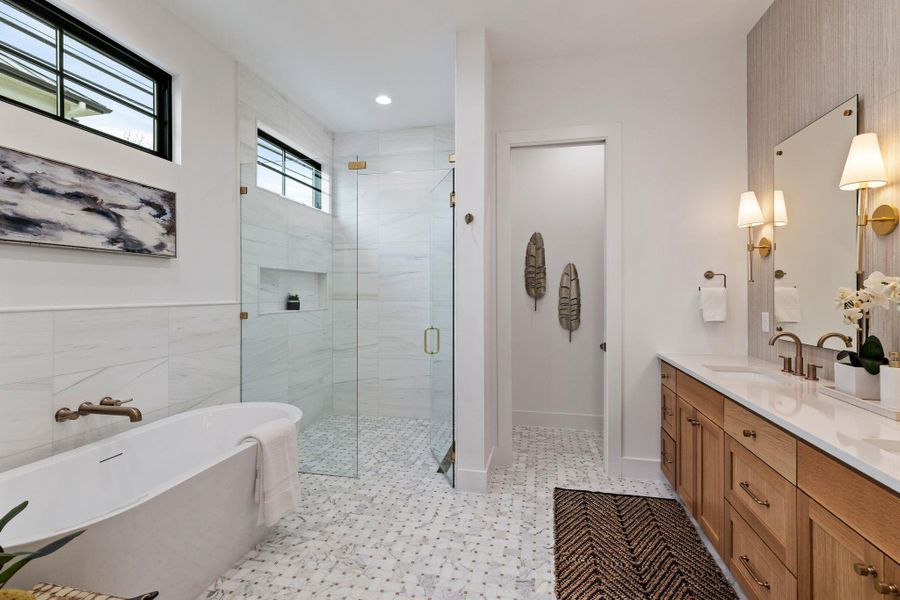 Bathroom with a stall shower, double vanity, a soaking tub, and baseboards