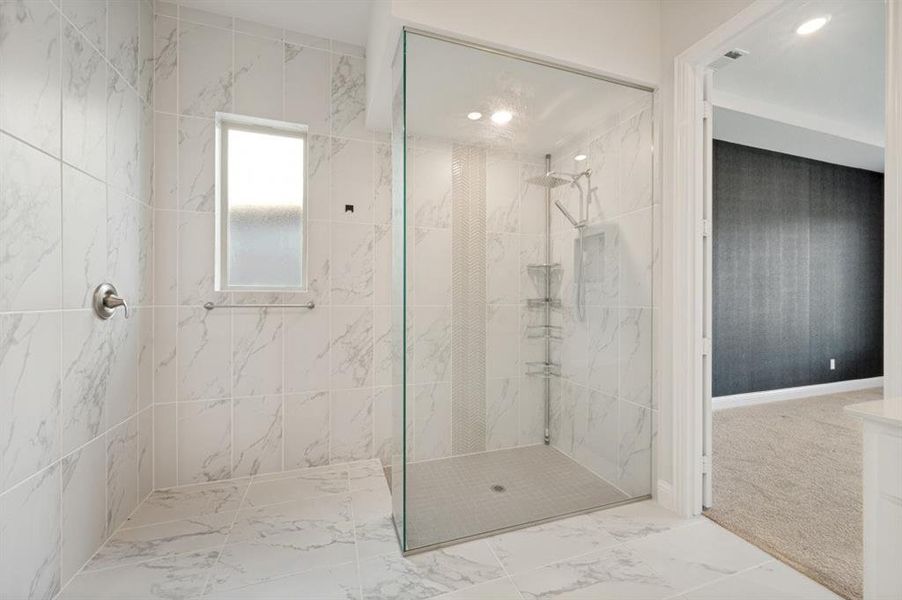 Spacious shower enclosure featuring full-height marble-look tile, a frameless glass panel, and a tiled shower pan