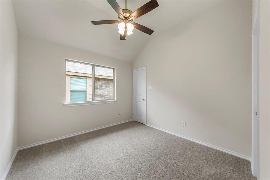 Empty room with a ceiling fan, carpet, vaulted ceiling, and baseboards Empty room with a ceiling fan, carpet, vaulted ceiling, and baseboards
