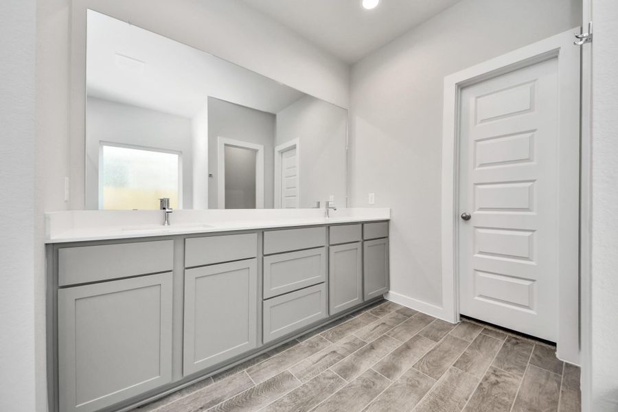 Escape to a spa-like oasis in this primary bathroom. Enjoy a walk-in shower with tile surround, a separate garden tub with custom detailing, and an elegant vanity featuring light countertops, modern hardware, and beautiful vanity lights. Experience luxury and relaxation in every detail. Sample photo of completed home with similar floor plan. Actual colors and selections may vary.