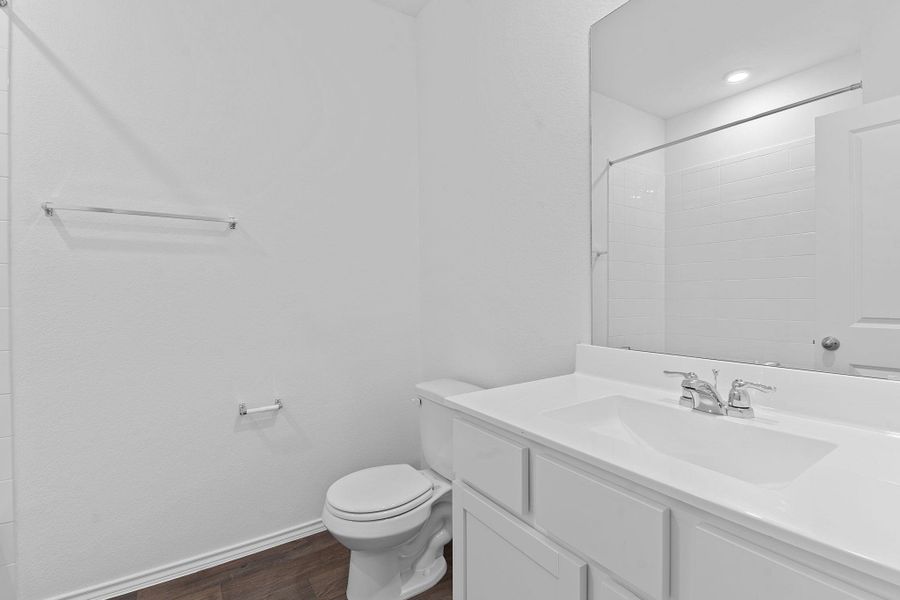 Bathroom with baseboards, a shower, toilet, wood finished floors, and vanity