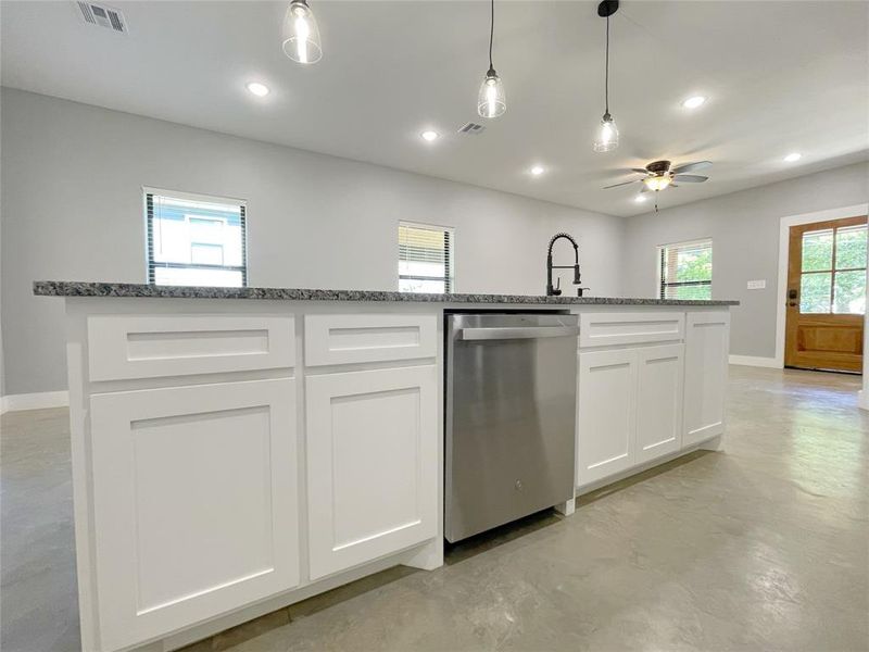 Kitchen featuring stone countertops, an island with sink, stainless steel dishwasher, ceiling fan, and white cabinets