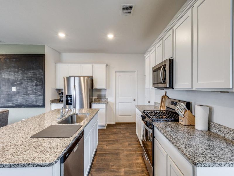 Kitchen featuring stainless steel appliances, dark wood-style floors, white cabinetry, light stone countertops, and recessed lighting