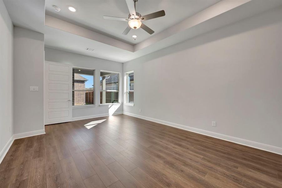 Unfurnished room featuring ceiling fan, a raised ceiling, dark wood finished floors, and recessed lighting