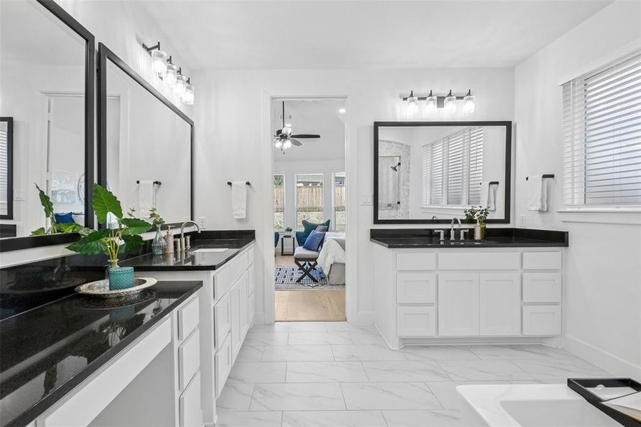Ensuite bathroom featuring light marble finish flooring, two vanities, and ceiling fan Ensuite bathroom featuring light marble finish flooring, two vanities, and ceiling fan