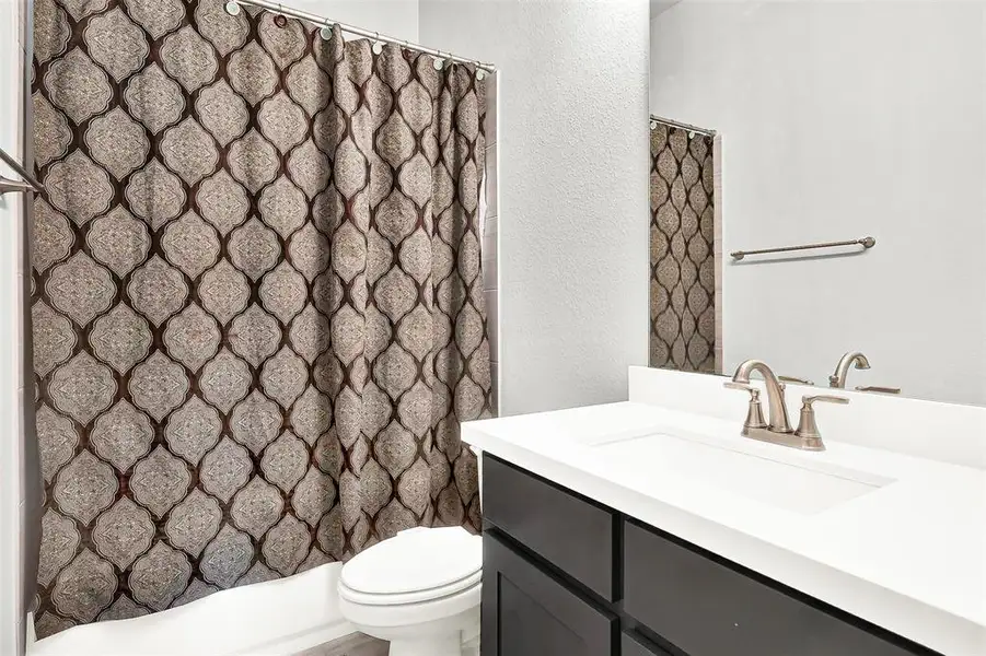 Full bathroom featuring vanity, a shower with curtain, and a textured wall Full bathroom featuring vanity, a shower with curtain, and a textured wall