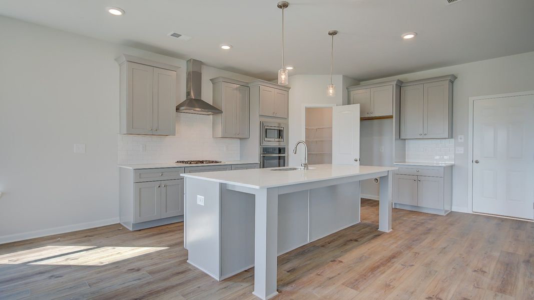 McKinley II modern kitchen with bright white cabinetry, tile backsplash, and large island with seating at Brighton.
