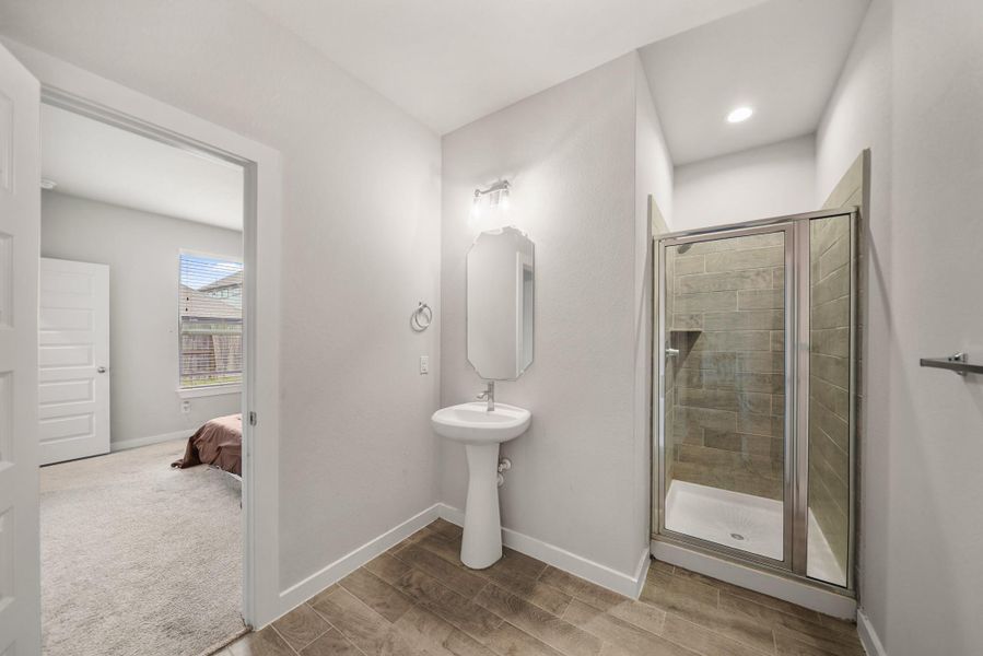 This room is complete with its own private bathroom. It includes tile floors, recessed lighting, and a walk-in shower.