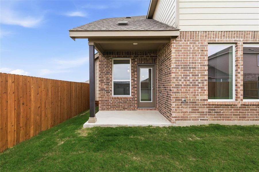 Covered patio with a concrete slab, brick exterior, and a private wood fence