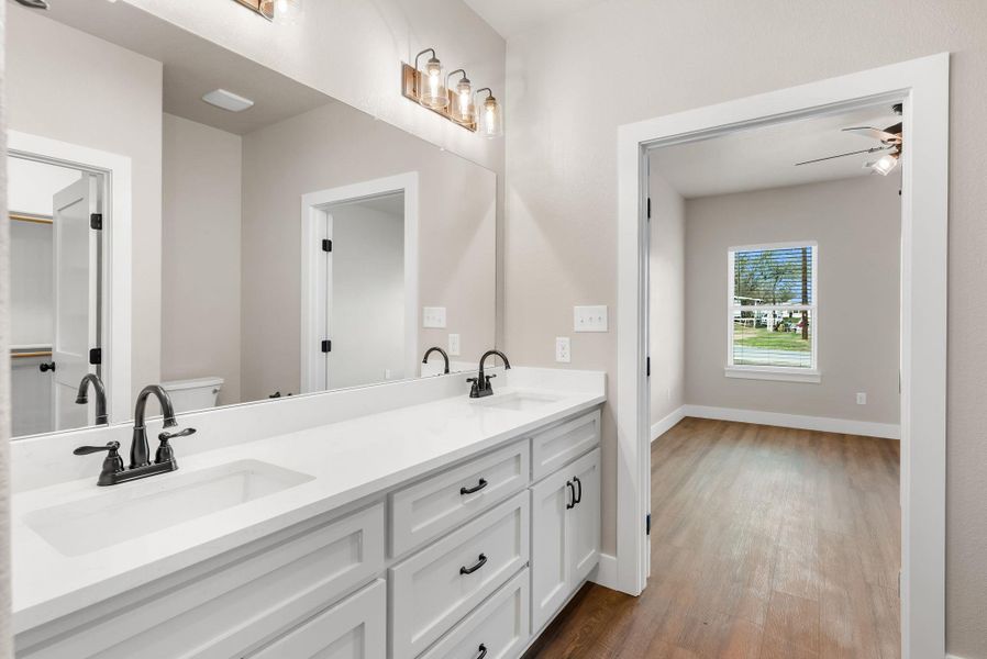 Bathroom featuring double vanity, light wood finished floors, and ceiling fan