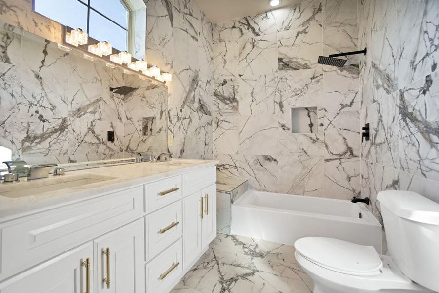 Bathroom featuring vanity, toilet, and tile walls