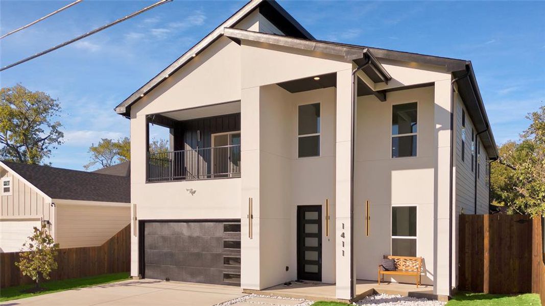 View of front facade featuring stucco siding, driveway, and an attached garage