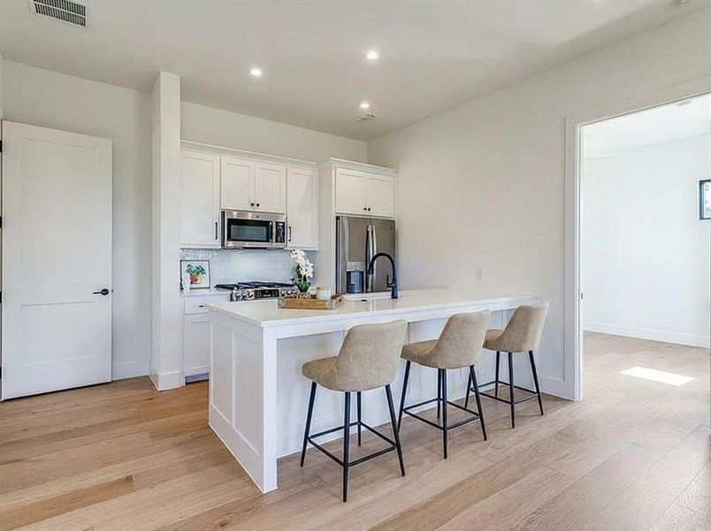 In-law suite Virtual Staged Kitchen featuring tasteful backsplash, white cabinetry, a peninsula, recessed lighting, and appliances with stainless steel finishes In-law suite Virtual Staged Kitchen featuring tasteful backsplash, white cabinetry, a peninsula, recessed lighting, and appliances with stainless steel finishes