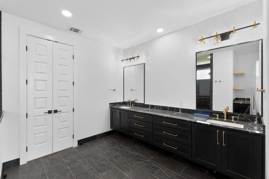 Bathroom with double vanity, recessed lighting, and a closet