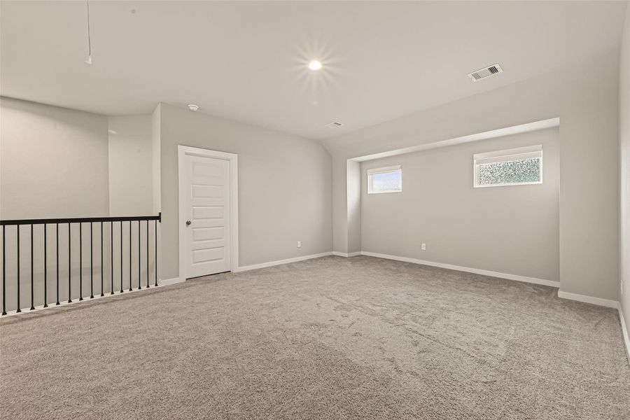 Another view of the game room shows its open space, with a closed door that provides access to a secondary bedroom.