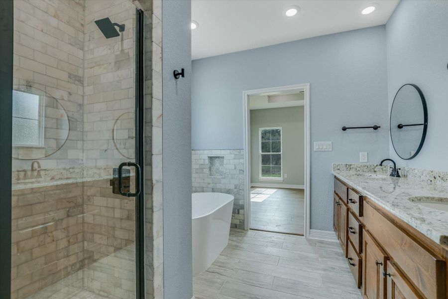 Bathroom with a freestanding bath, a shower stall, and double vanity