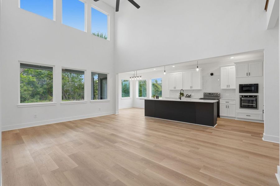 This spacious, open-plan kitchen and living area features high ceilings, abundant natural light from large windows, and modern finishes.