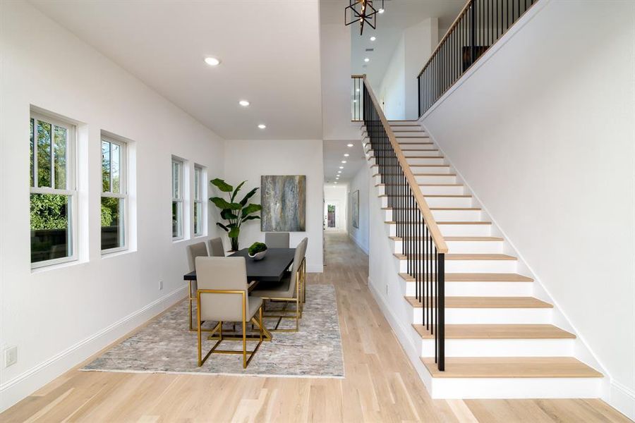 Dining space with a towering ceiling and light hardwood / wood-style flooring