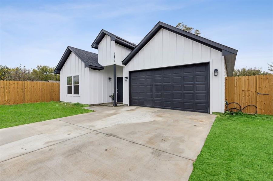 Modern farmhouse style home with a front yard and a garage