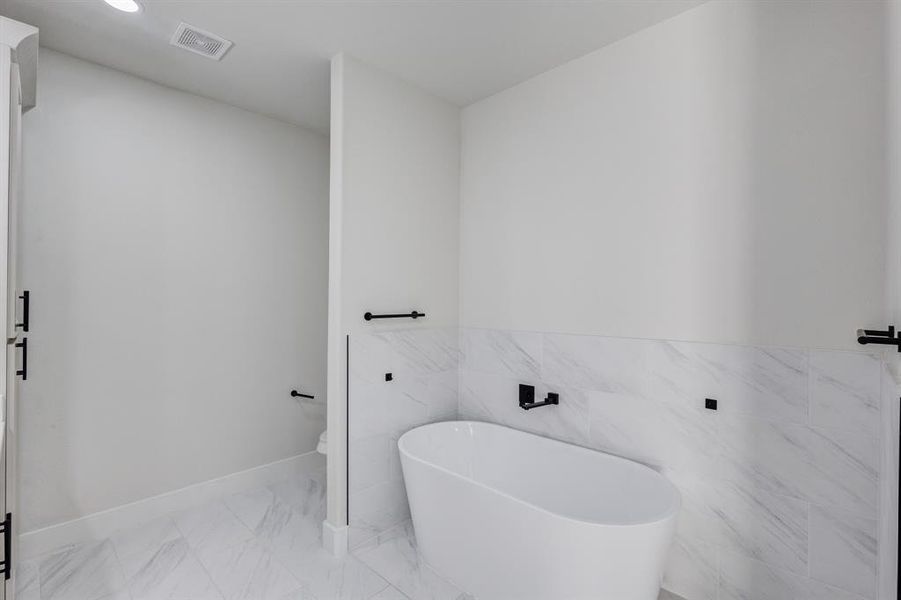 Bathroom featuring a bath and tile walls