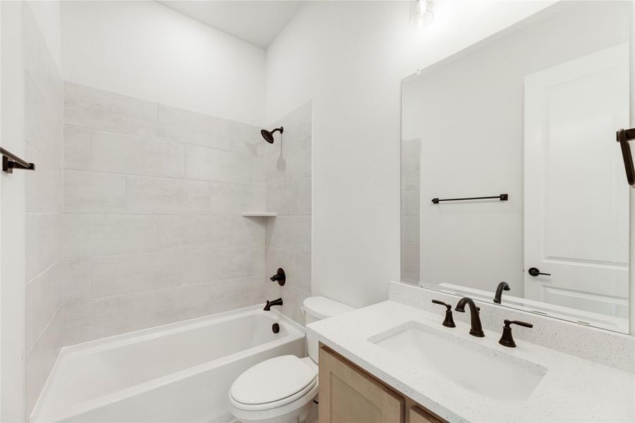 Bathroom with tiled tub-shower combo, white quartz vanity, and dark bronze fixtures