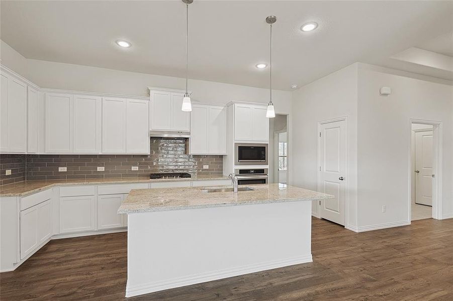 Kitchen featuring white cabinetry, stainless steel appliances, hanging light fixtures, and dark hardwood / wood-style floors