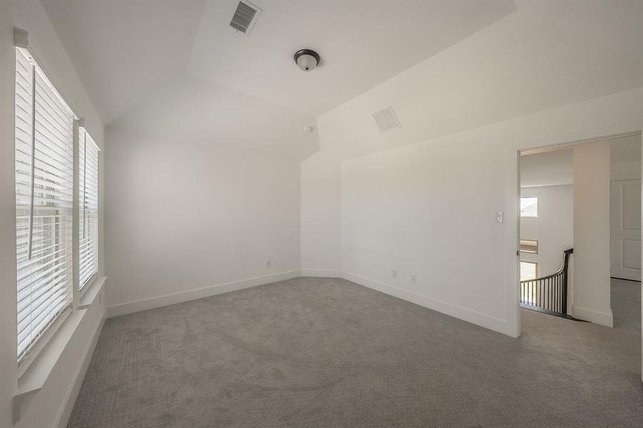 This room features light gray carpeting, white walls, and a vaulted ceiling