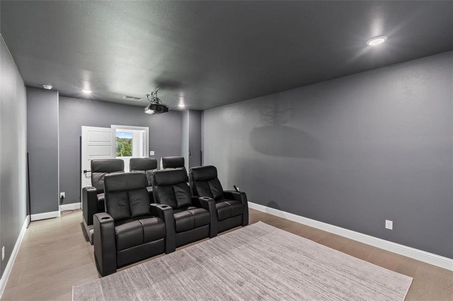 Cinema room with baseboards and light wood-type flooring