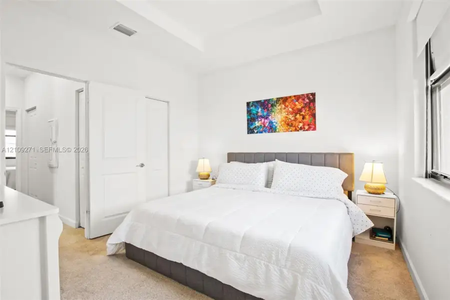 Tray ceiling, neutral carpeted flooring, and multi-panel interior doors