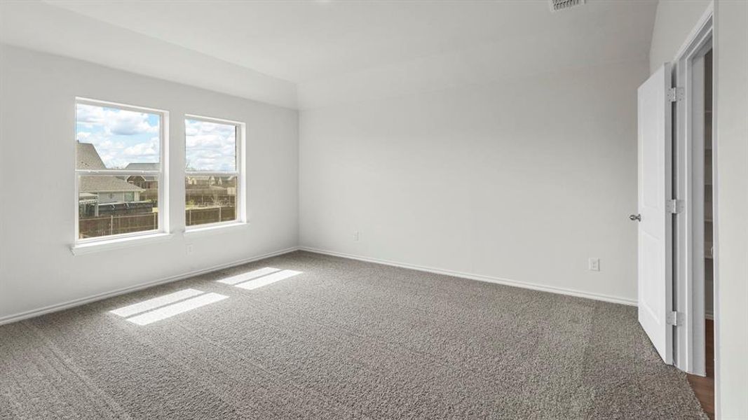 This room features a neutral color palette, two large windows providing natural light, and plush grey carpeting