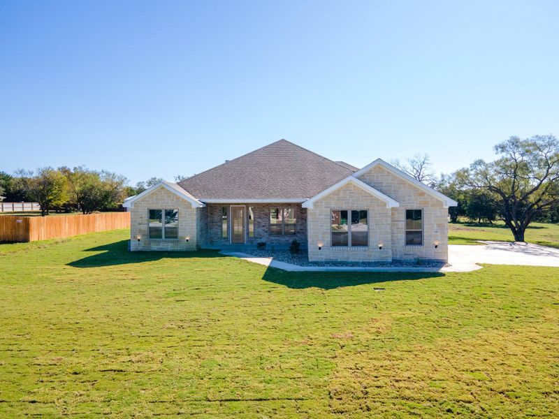 View of front of home with a shingled roof, stone siding, and brick siding
