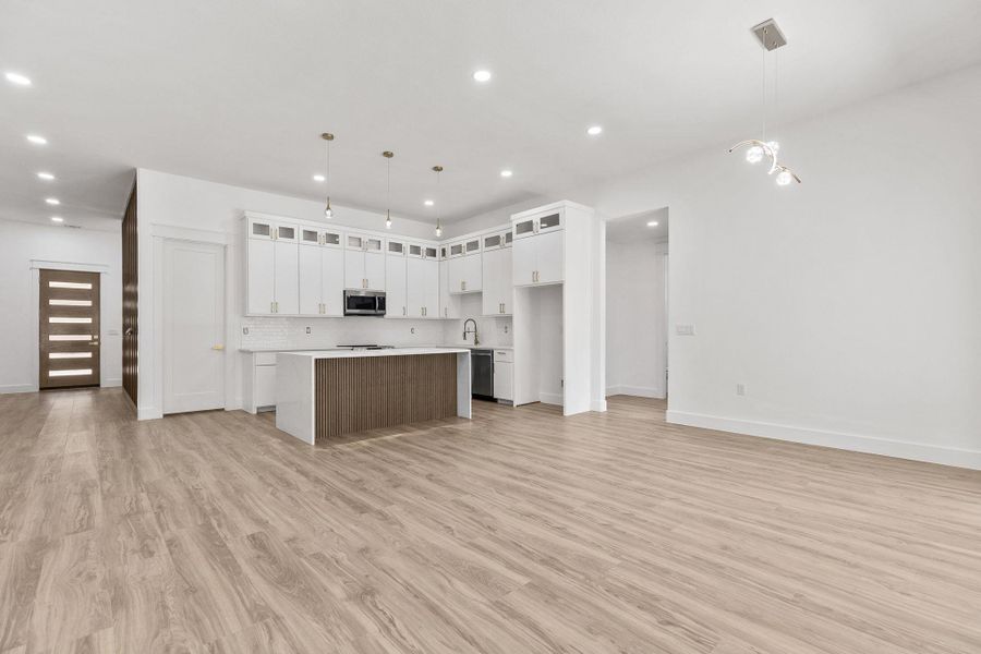 Kitchen featuring open floor plan, a center island, glass insert cabinets, hanging light fixtures, and two tone color scheme