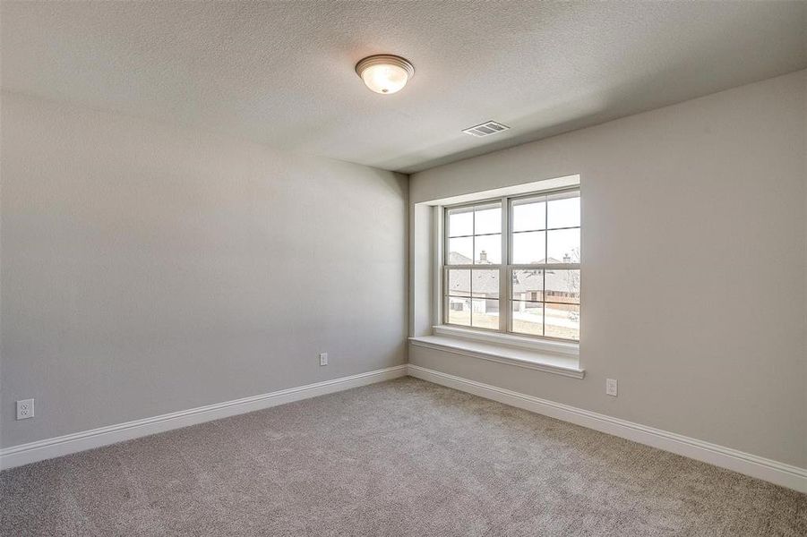 Empty room featuring light colored carpet and a textured ceiling