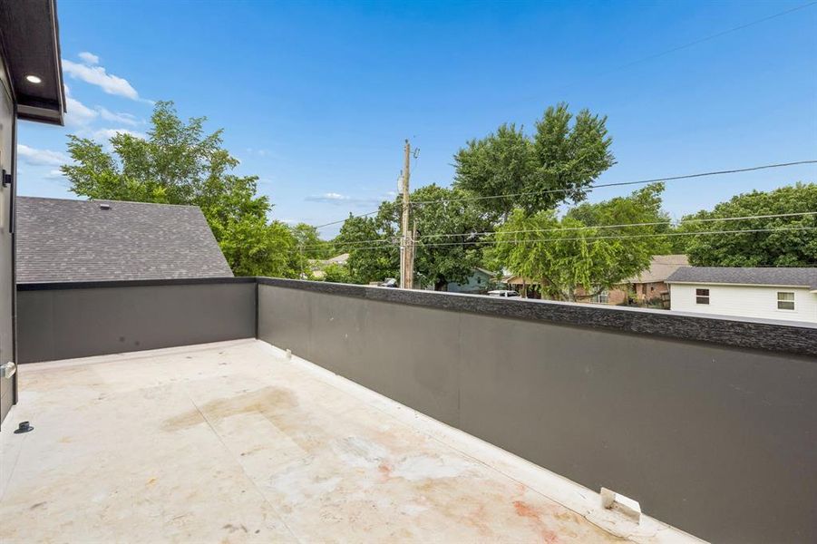 Private rooftop deck featuring a flat surface, dark gray perimeter walls, and an exterior overhead light fixture Private rooftop deck featuring a flat surface, dark gray perimeter walls, and an exterior overhead light fixture