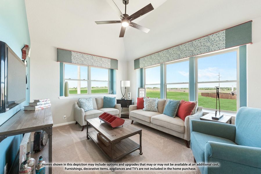 Living room with vaulted ceiling, ceiling fan, large windows, and neutral sofas with colorful accent pillows Living room with vaulted ceiling, ceiling fan, large windows, and neutral sofas with colorful accent pillows