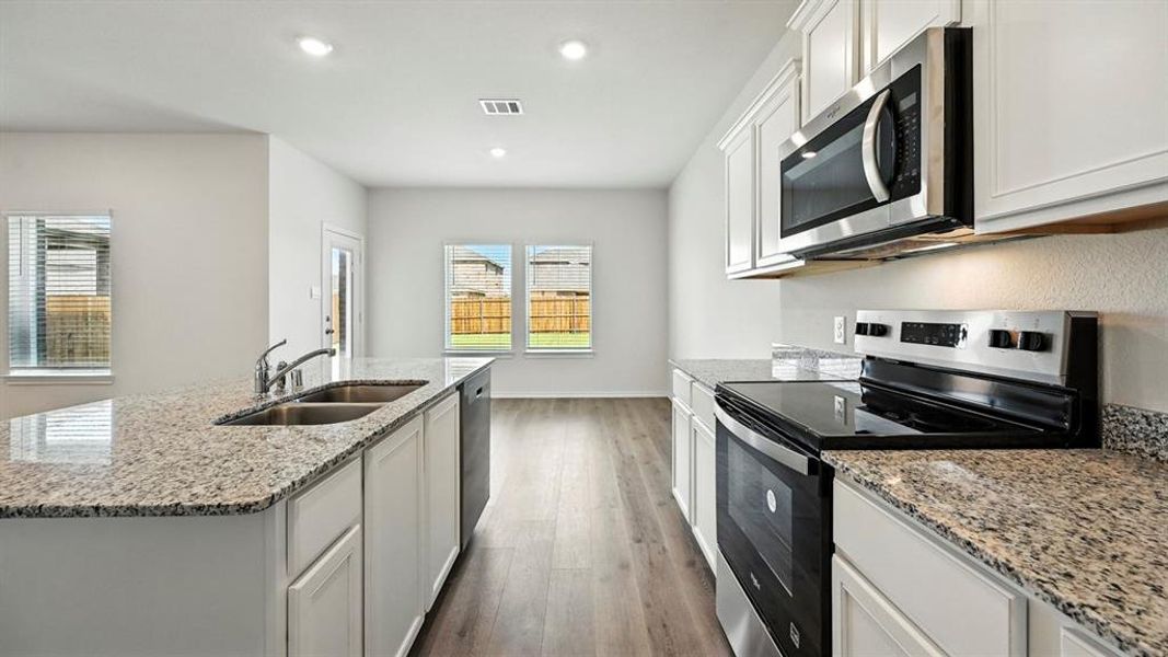 Kitchen featuring stainless steel appliances, white cabinets, light stone countertops, dark wood-style floors, and recessed lighting