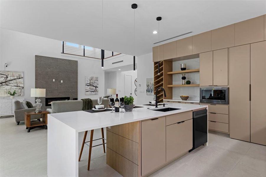 Kitchen featuring stainless steel microwave, sink, a fireplace, hanging light fixtures, and a center island with sink