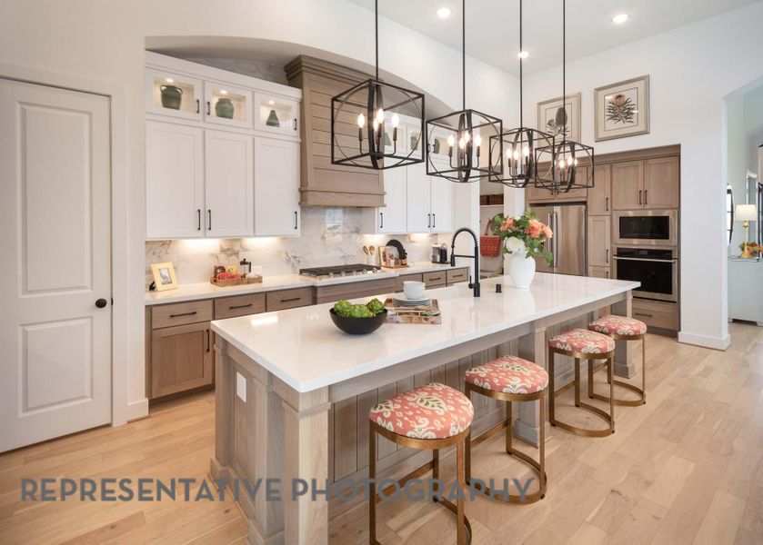 Kitchen with a notable chandelier, a sink, a kitchen breakfast bar, light wood-style flooring, and stainless steel appliances Kitchen with a notable chandelier, a sink, a kitchen breakfast bar, light wood-style flooring, and stainless steel appliances