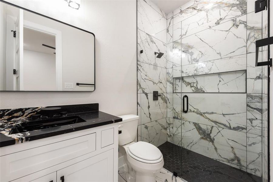 Full bath with vanity, toilet, and a marble finish shower Full bath with vanity, toilet, and a marble finish shower