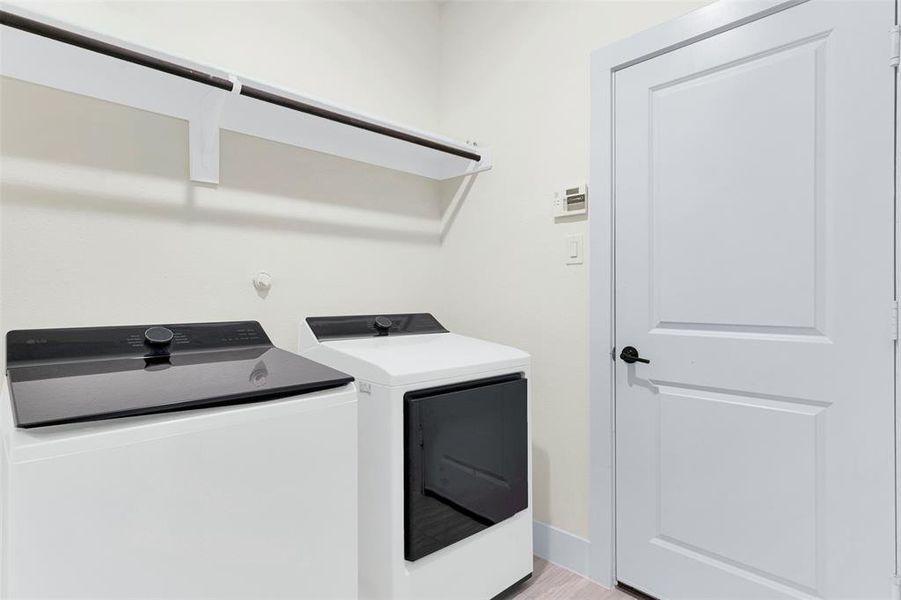 Laundry area with washing machine and dryer and light wood-style flooring Laundry area with washing machine and dryer and light wood-style flooring