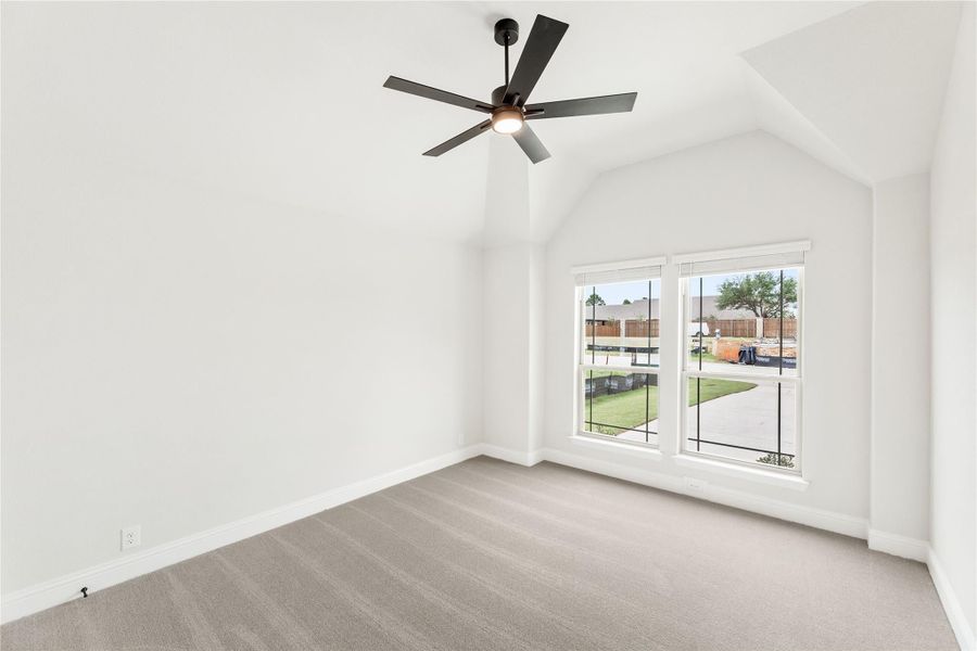 Empty bedroom with vaulted ceiling, ceiling fan, carpet flooring, and large window