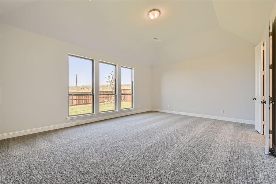 Carpeted spare room featuring vaulted ceiling