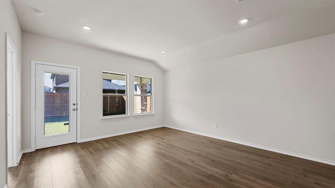 Empty room with dark wood-type flooring, vaulted ceiling, and recessed lighting