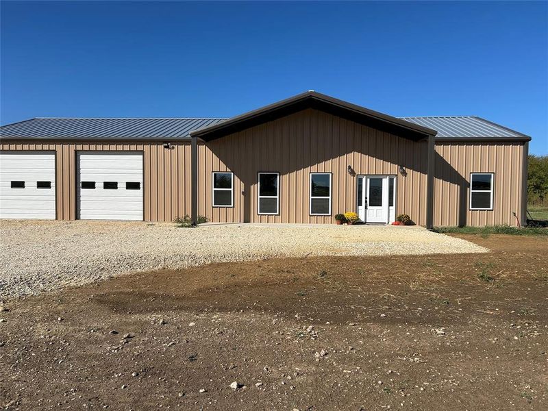 View of front facade with a metal roof, board and batten siding, and a garage